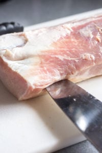 a large knife cutting into the edge of a pork roast