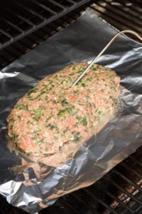 uncooked meatloaf on the grill with a temp probe