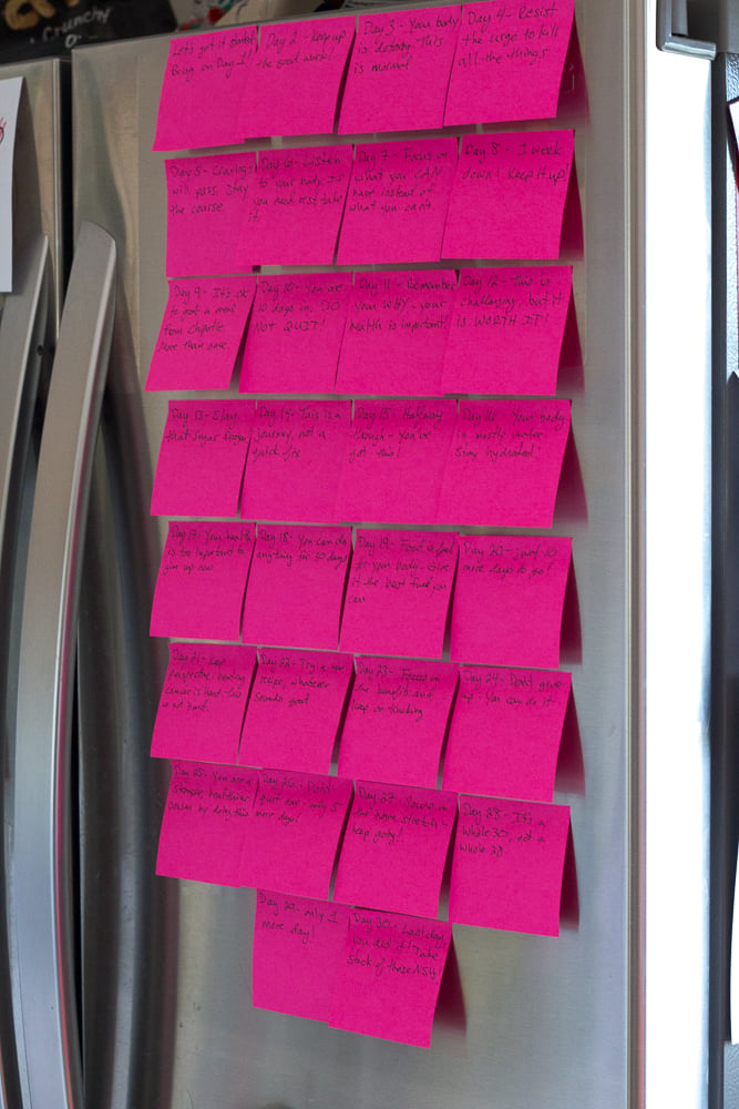 pink post it notes on a silver fridge