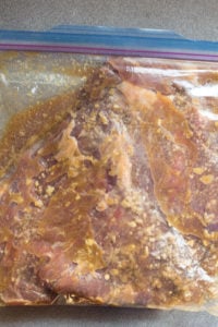 flank steak marinating in a sealed plastic bag