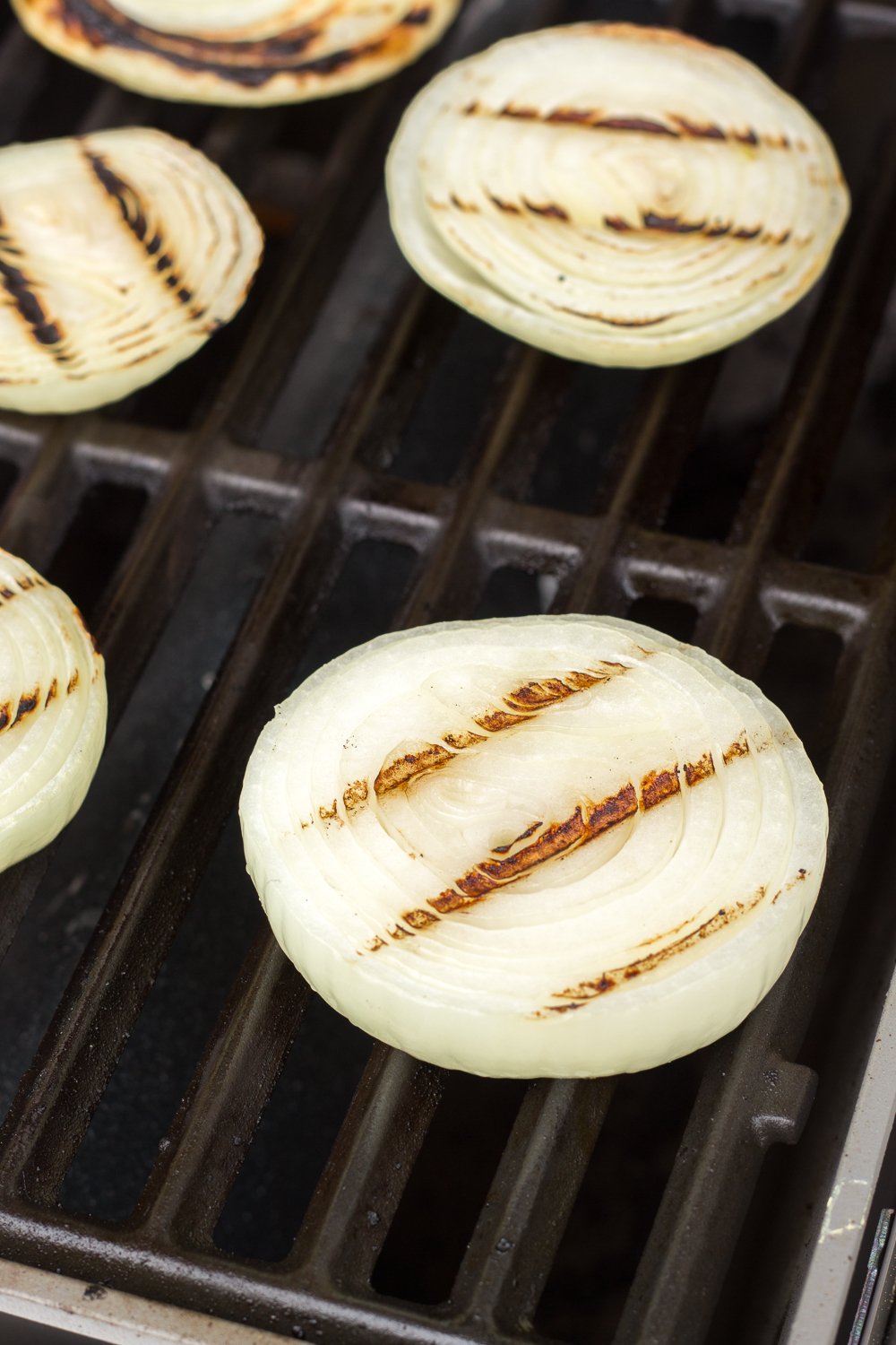 Slices of grilled onions on the grill grates.