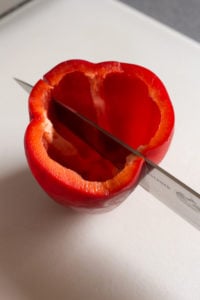 cutting a red bell pepper into two halves