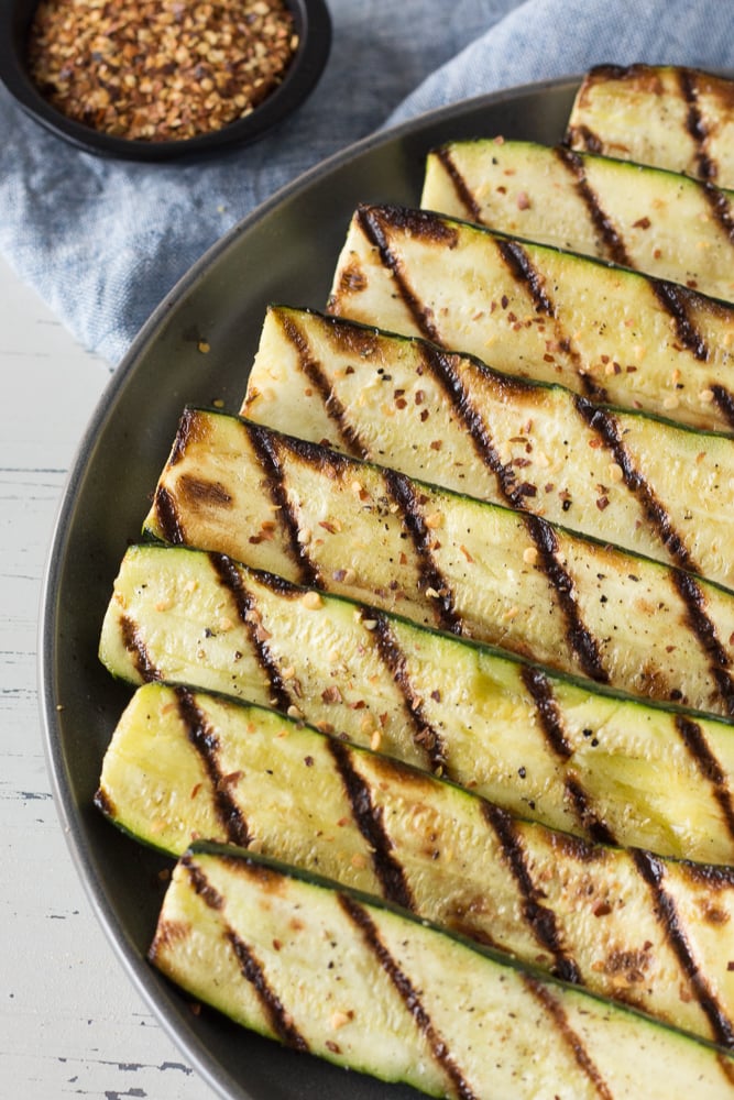 grilled zucchini on a grey plate with red pepper flakes