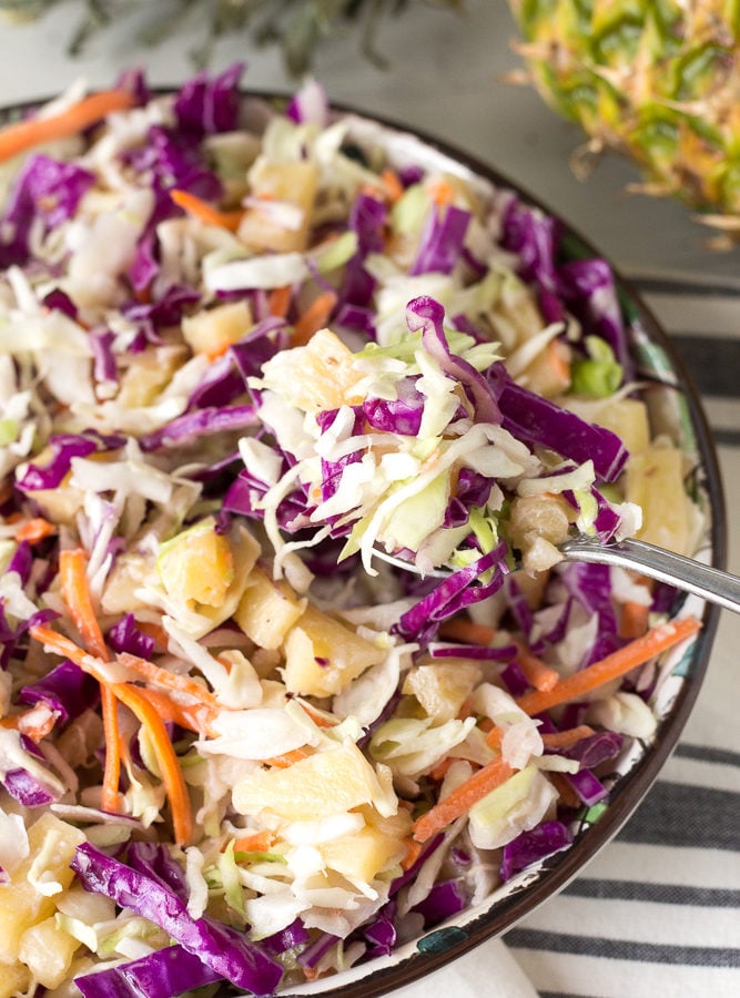 Close up of pineapple coleslaw in a bowl with a spoonful coming out.