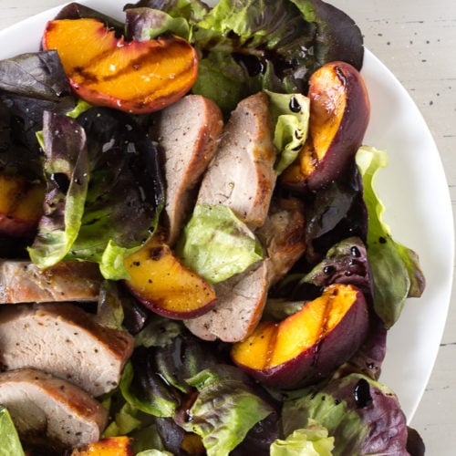 grilled peach and pork salad on a white platter