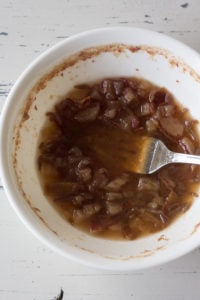 a fork mashing up dates in a bowl of water
