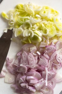 sliced leeks and shallots on a cutting board