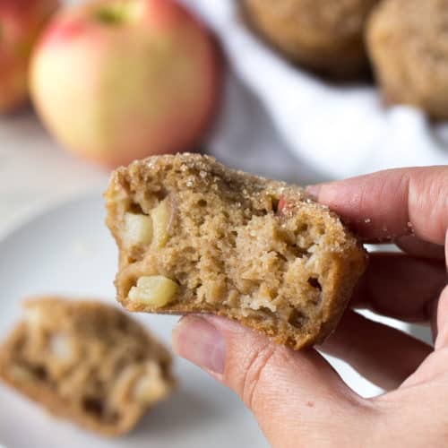 a hand holding half an apple cinnamon muffin