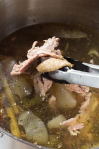 removing cooked bones from a large pot of turkey stock