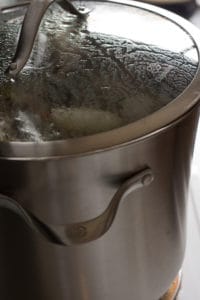 a large pot of turkey stock coming to a boil on the stove