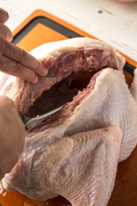 a turkey on a cutting board with one side of the backbone cut