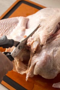 making a second incision on the other side of the backbone of a raw turkey