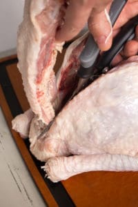 cutting the backbone out of a raw turkey