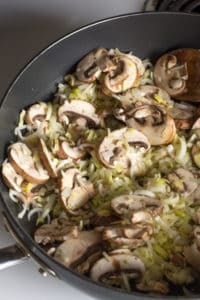 chopped leeks and sliced mushrooms cooking in a pan