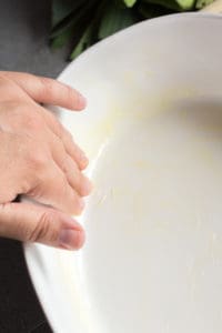 a handing greasing a casserole dish