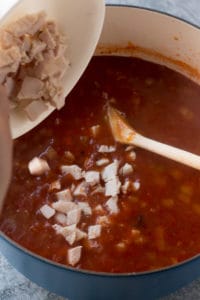 adding chopped turkey into the tortilla soup