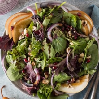 top down shot of pear salad in a gray bowl with ingredients surrounding it