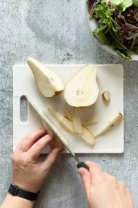 overhead shot of hands slicing a pear on a cutting board