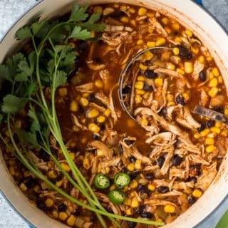 a large pot of black bean chicken chili garnished with jalapeno and parsley