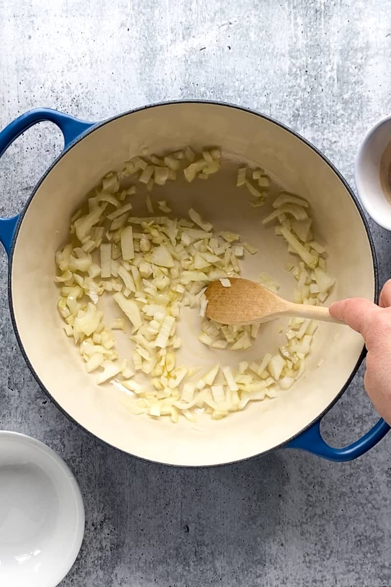 diced onion and garlic being stirred in a large pot