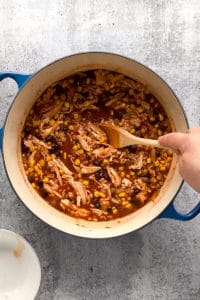 stirring chicken into a pot of chili