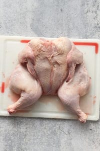 a raw spatchcock chicken on a cutting board