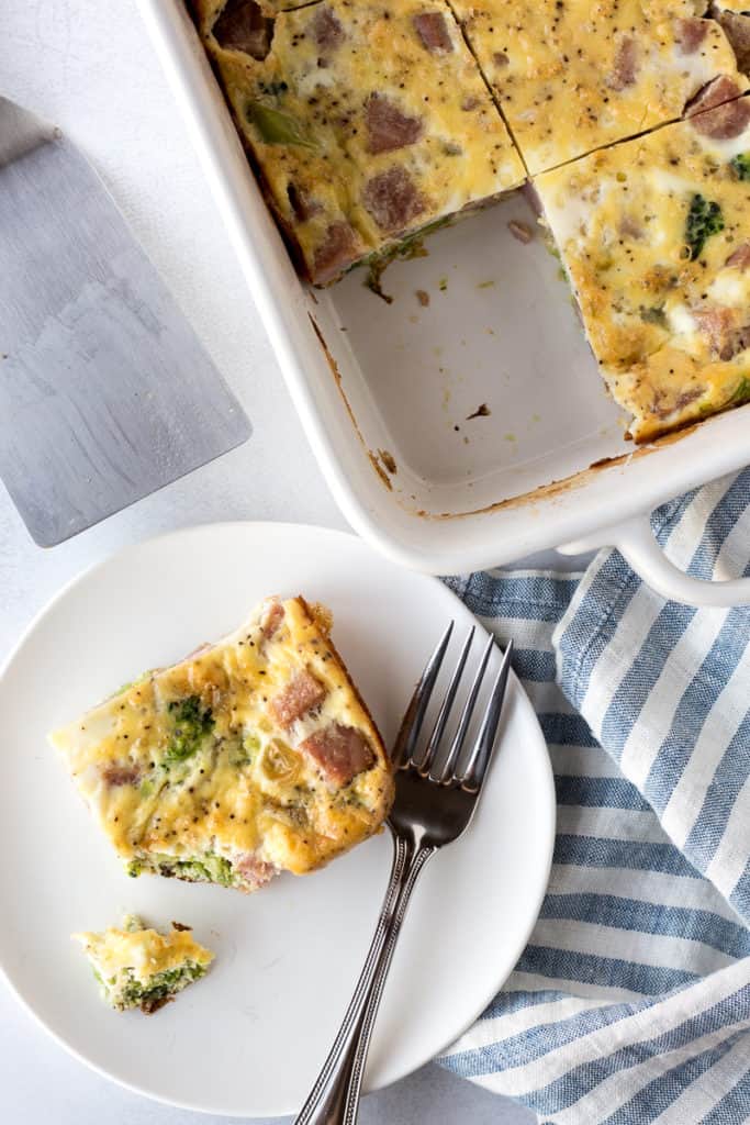 a pice of breakfast casserole on a plate next to the casserole dish
