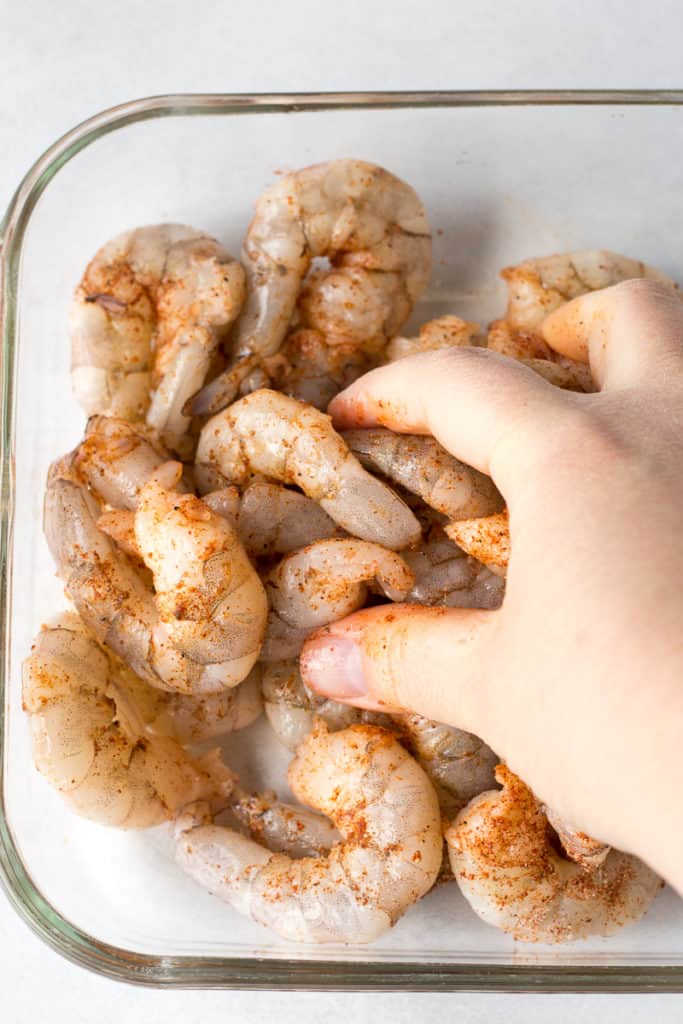 rubbing seasoning on shrimp with a hand