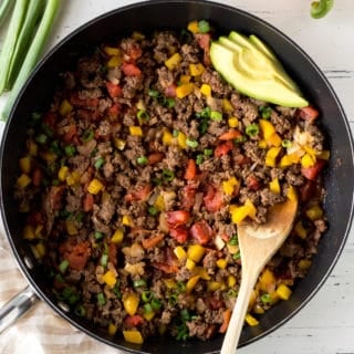 top down shot of a skillet filled with paleo ground beef and toppings surrounding it