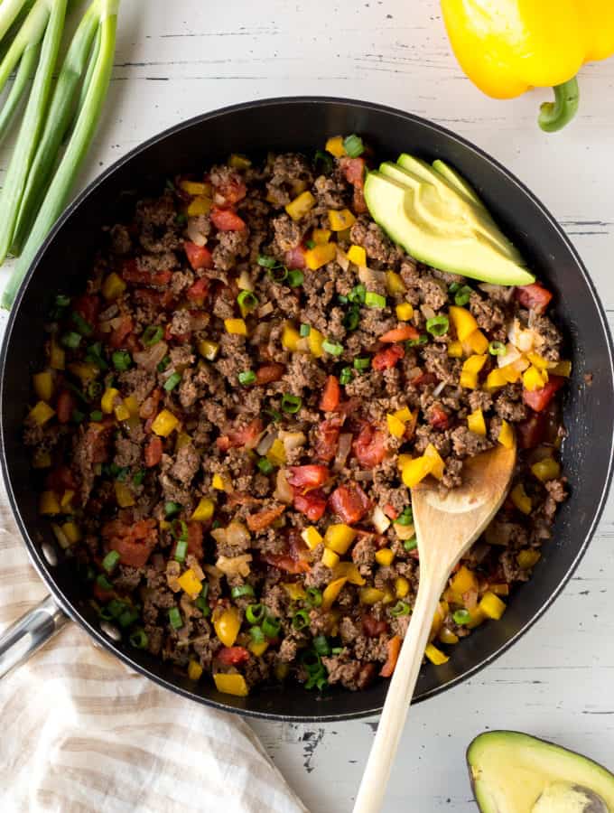 top down shot of a skillet filled with paleo ground beef and toppings surrounding it