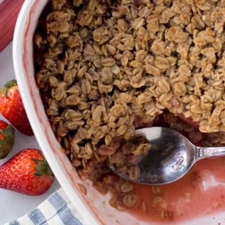 top down shot of gluten free strawberry rhubarb crisp in a bake dish with a spoon in it