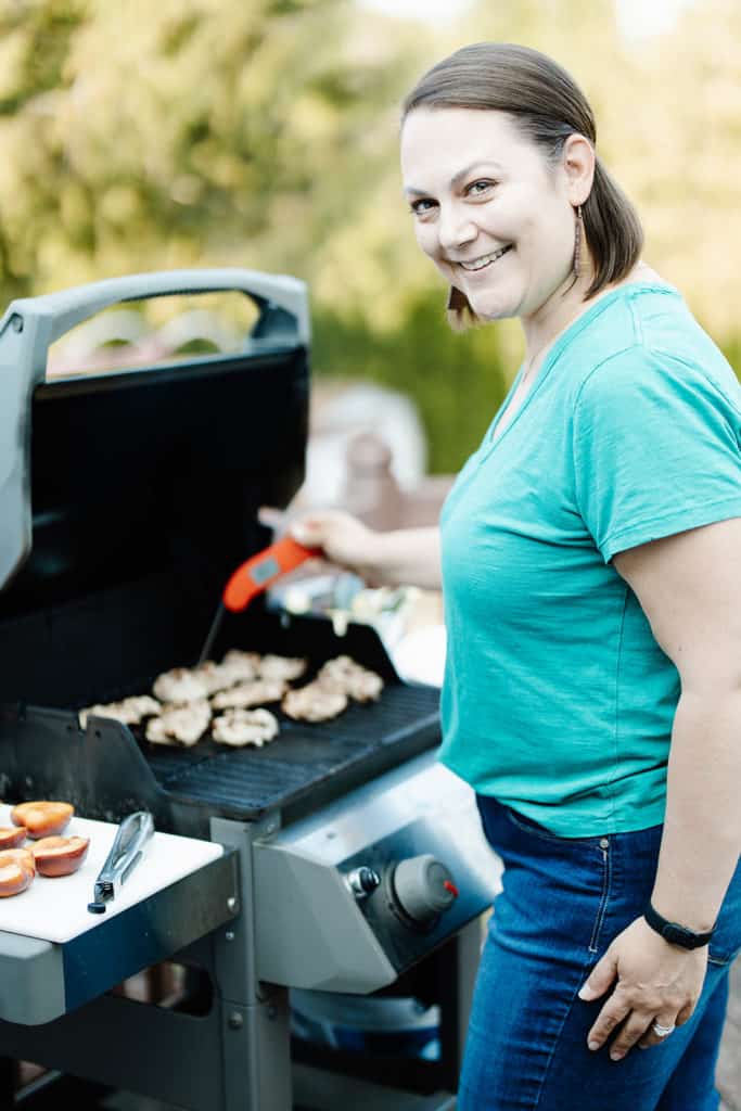 Taryn Solie checking the temp of chicken thighs on a grill with a Thermapen