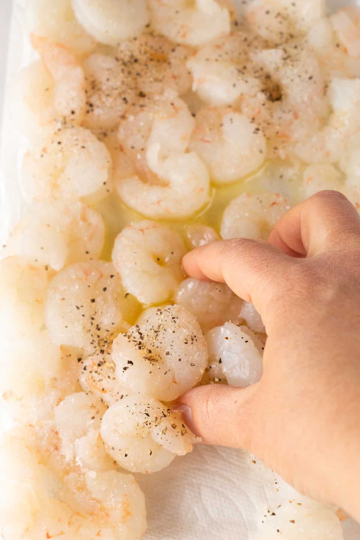 Stirring raw shrimp with a hand.