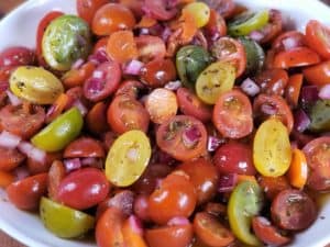 Close up of a sliced cherry tomato salad with different colors of tomatoes in a white bowl.
