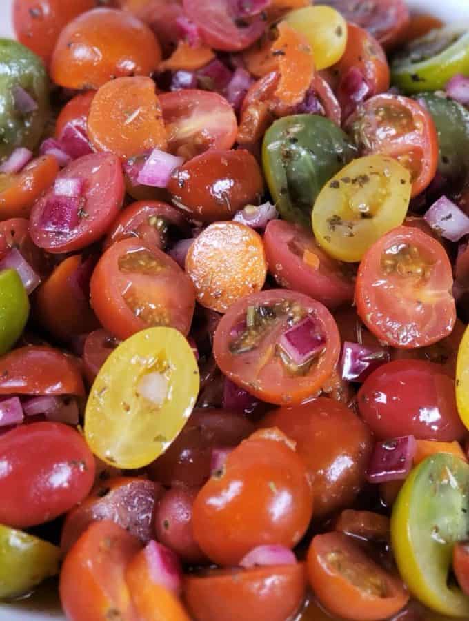 Close up of a sliced cherry tomato salad with different colors of tomatoes in a white bowl.