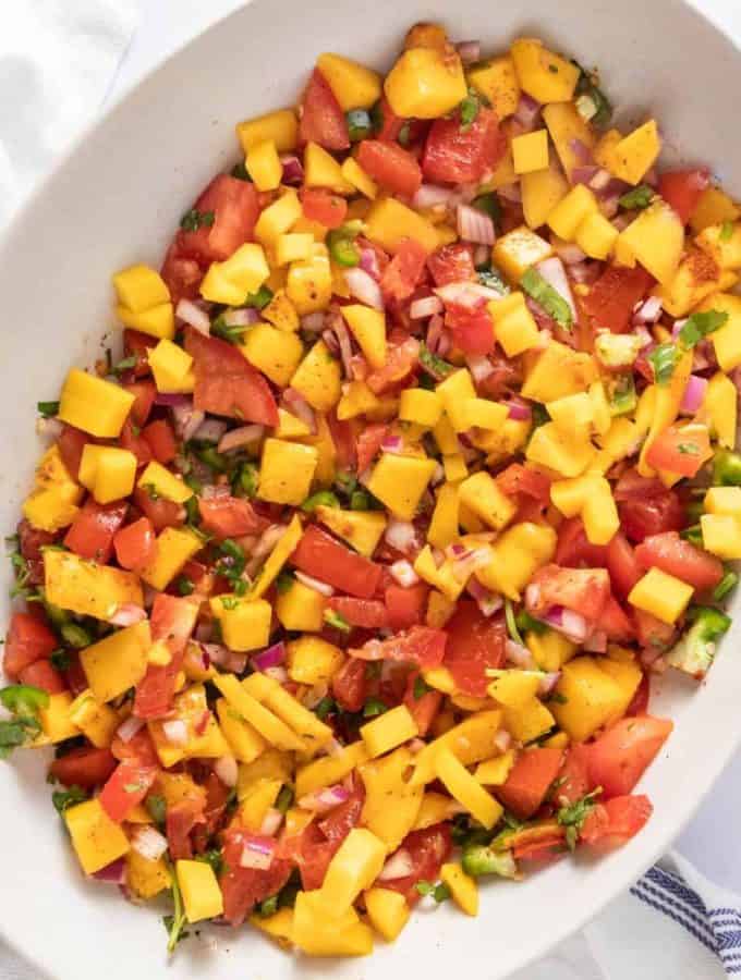 Top down shot of a large white serving dish with mango salsa in it.