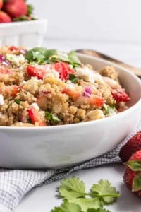 Side shot of a white bowl with a strawberry and quinoa salad in it.
