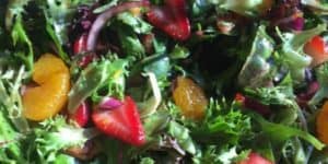 Close up of a citrus berry salad with purple onion.
