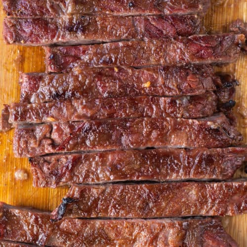 Top down close up of sliced smoked skirt steak on a wood cutting board.