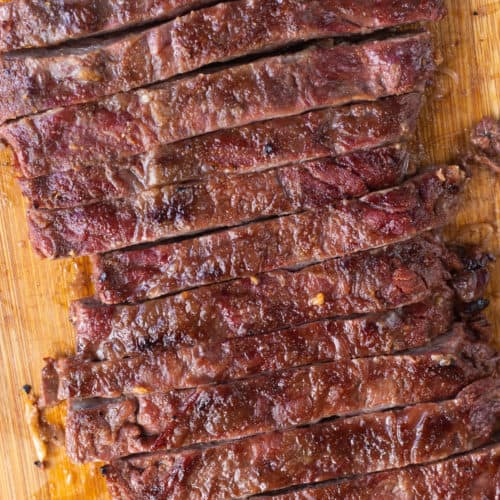 Top down close up of sliced skirt steak on a wood cutting board.