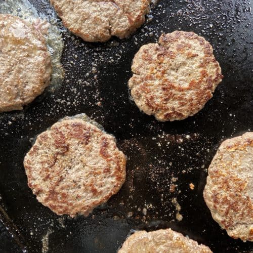 Close up of beef hamburger patties on a large griddle.