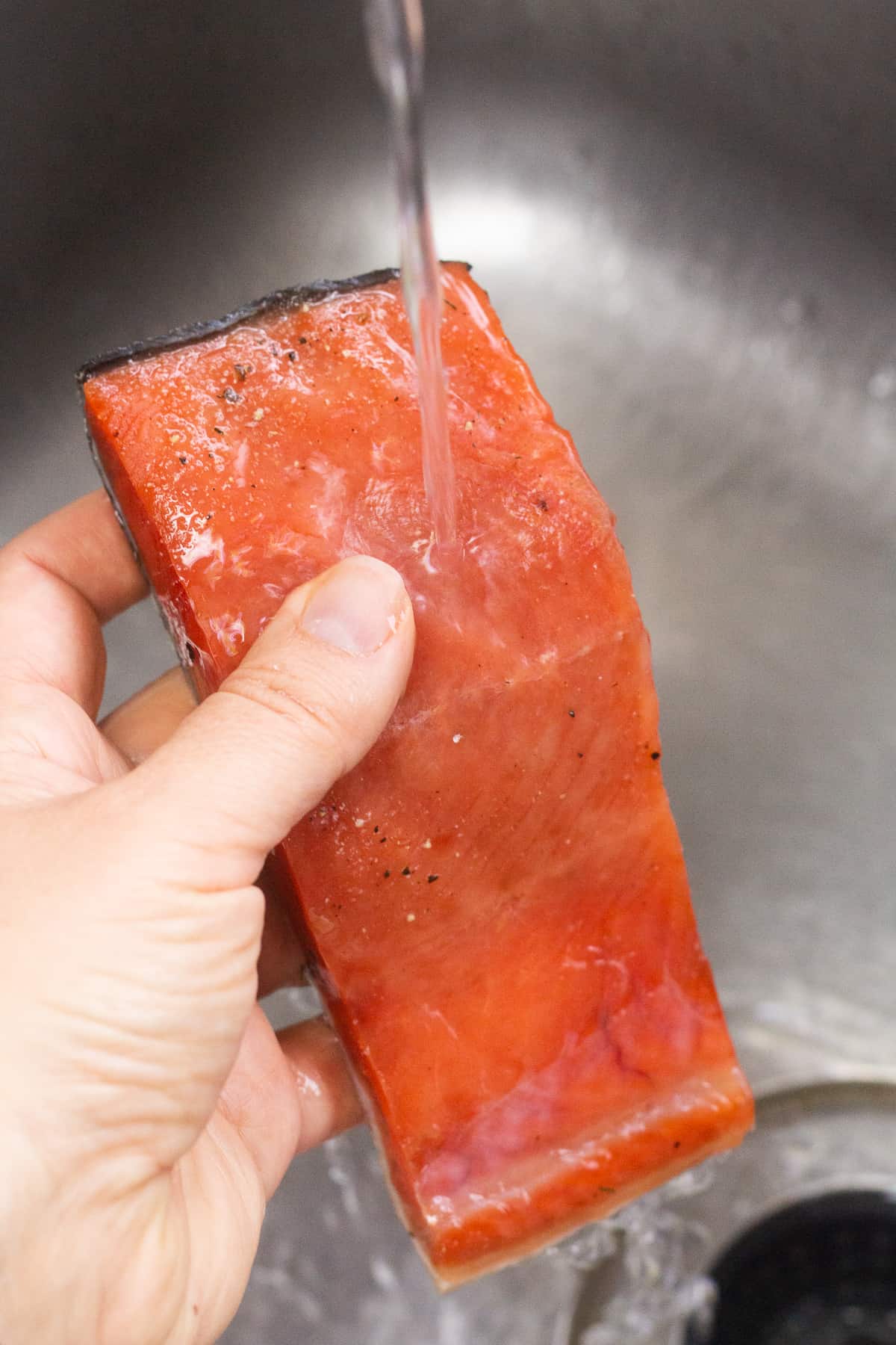 Close up of brined salmon being rinsed off in a sink.