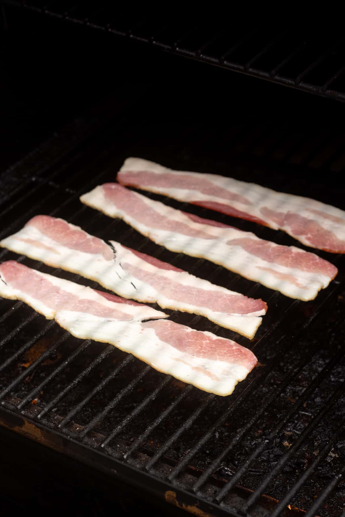Raw bacon slices on a traeger grill