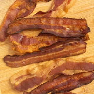 Top down shot of cooked bacon on a wood cutting board.
