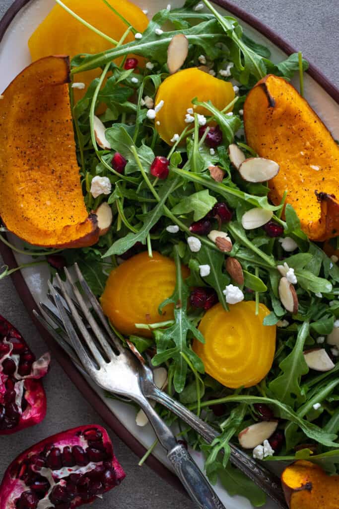 A top down shot of an arugula salad with pumpkin and golden beets.