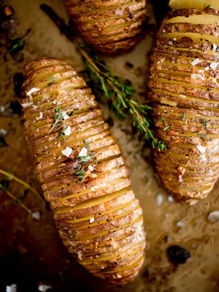 A top down shot of hasselback potatoes topped with garlic and herbs.