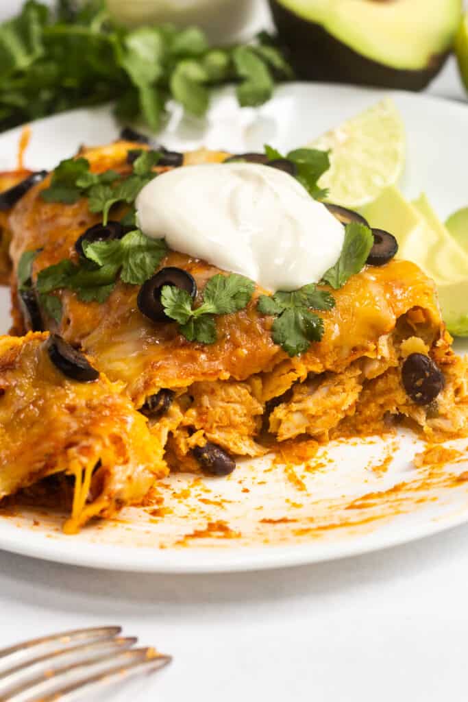 A turkey enchilada that's been cut into on a white plate.