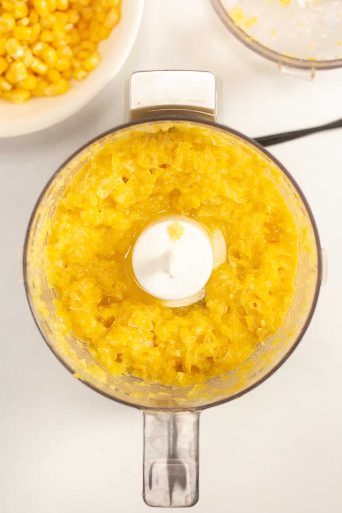 A top down image of corn and broth puree in a small food processor