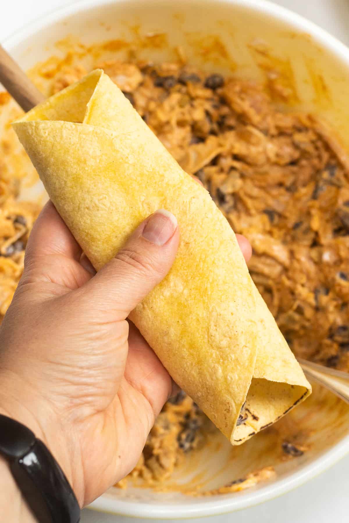 A rolled up enchilada in a hand.