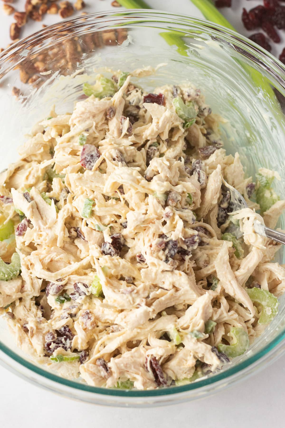 A clear bowl with cranberry pecan chicken salad mixed together in it.